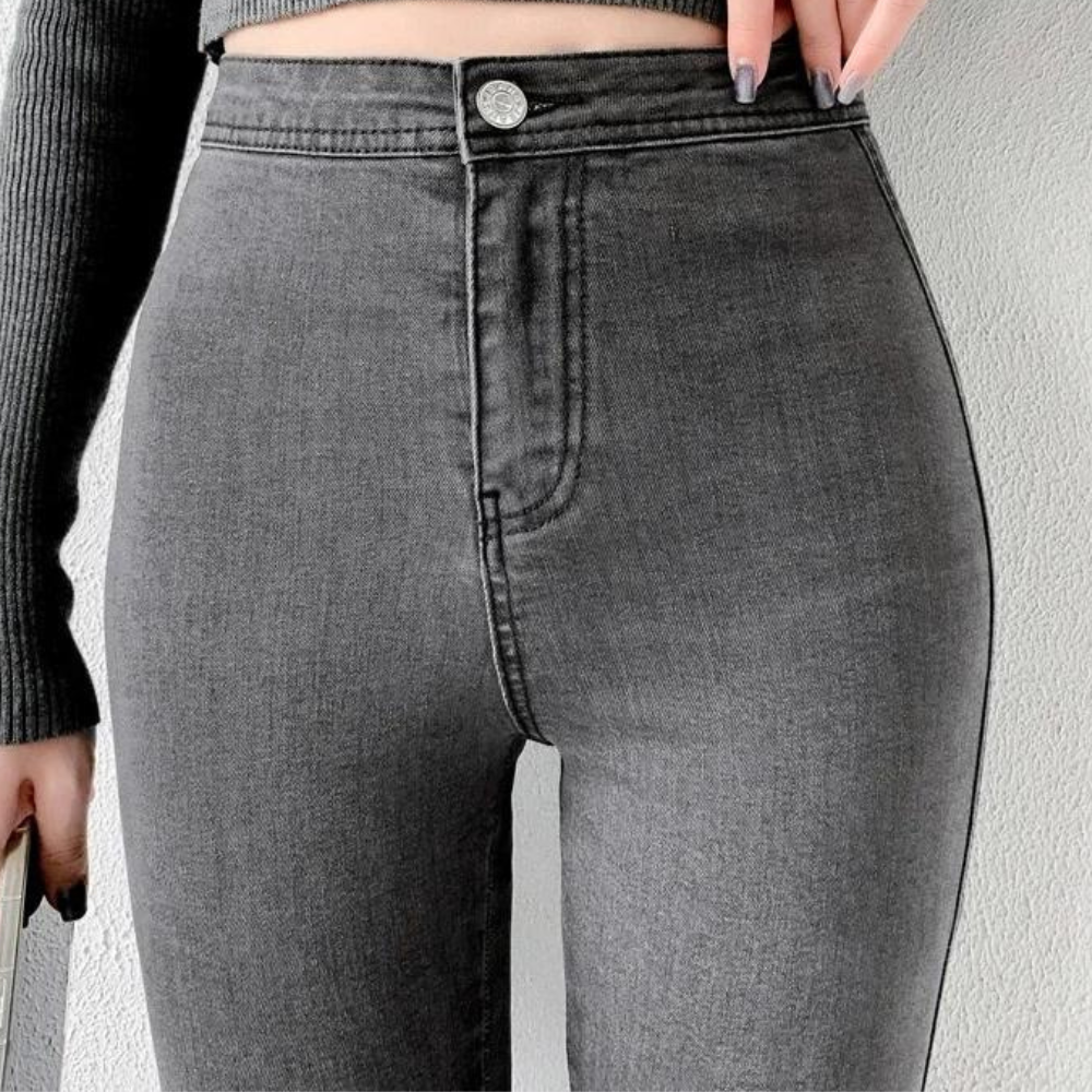 A pair of Cotton Elastic Denim Jeans in light blue, featuring a mid-waist fit, button fly closure, and sash and button decorations. These full-length pencil pants offer high stretch fabric for comfort and style, perfect for all occasions.