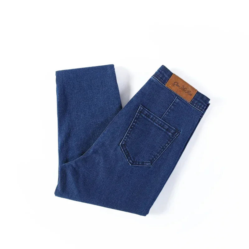 A pair of Cotton Elastic Denim Jeans in light blue, featuring a mid-waist fit, button fly closure, and sash and button decorations. These full-length pencil pants offer high stretch fabric for comfort and style, perfect for all occasions.