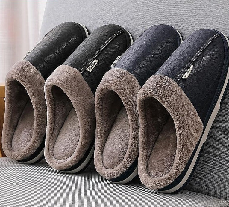 A pair of men's indoor slippers made of proportioned PU and plush insole material. The slippers are a light brown color and have a comfortable, relaxed design.