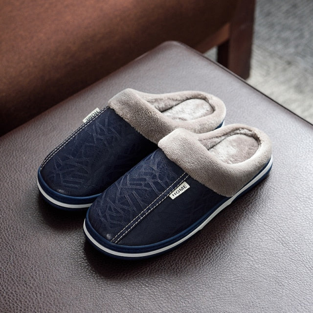 A pair of men's indoor slippers made of proportioned PU and plush insole material. The slippers are a light brown color and have a comfortable, relaxed design.