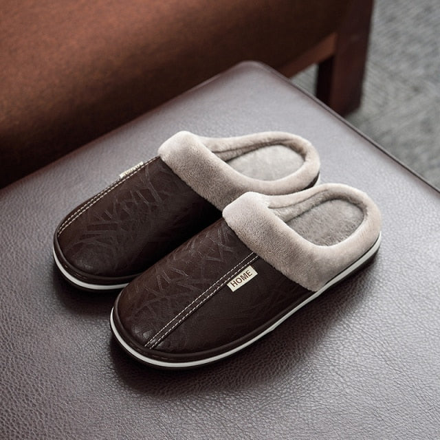A pair of men's indoor slippers made of proportioned PU and plush insole material. The slippers are a light brown color and have a comfortable, relaxed design.