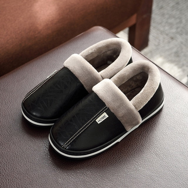 A pair of men's indoor slippers made of proportioned PU and plush insole material. The slippers are a light brown color and have a comfortable, relaxed design.