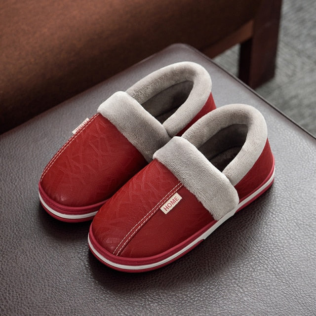 A pair of men's indoor slippers made of proportioned PU and plush insole material. The slippers are a light brown color and have a comfortable, relaxed design.