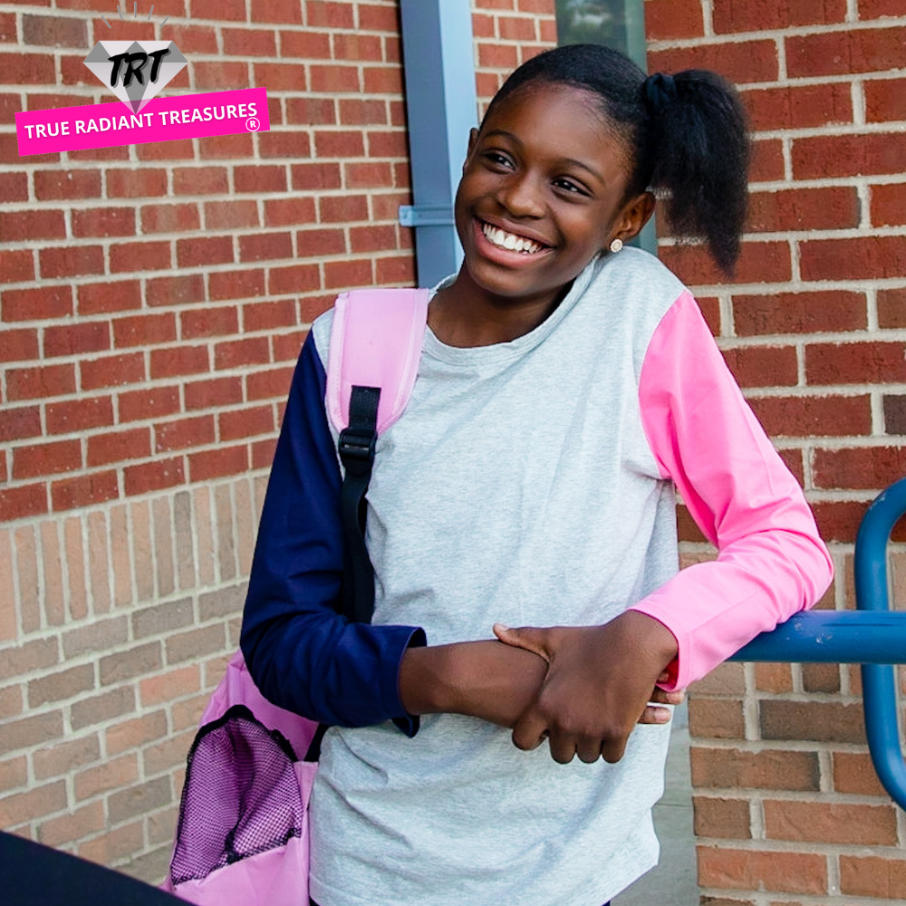 A young girl wearing a long sleeve shirt from True Radiant Treasures. The shirt is made from a soft polyester and cotton blend and comes in a variety of colors and patterns.