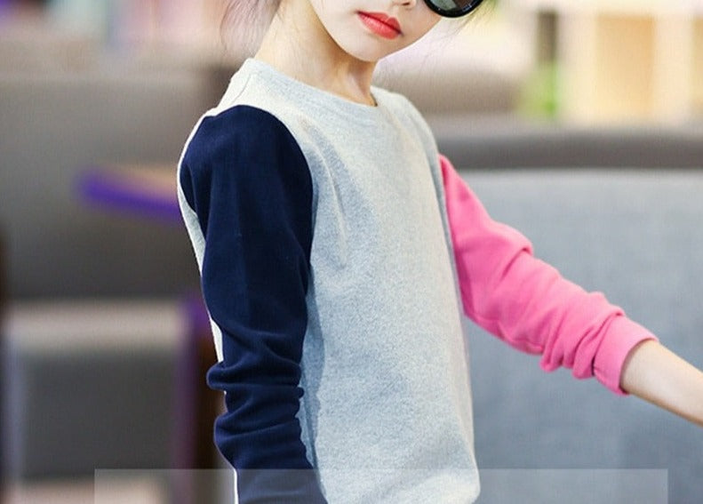 A young girl wearing a long sleeve shirt from True Radiant Treasures. The shirt is made from a soft polyester and cotton blend and comes in a variety of colors and patterns.