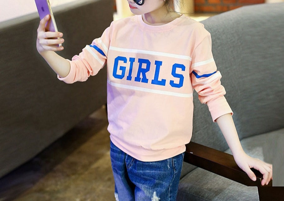 A young girl wearing a long sleeve shirt from True Radiant Treasures. The shirt is made from a soft polyester and cotton blend and comes in a variety of colors and patterns.