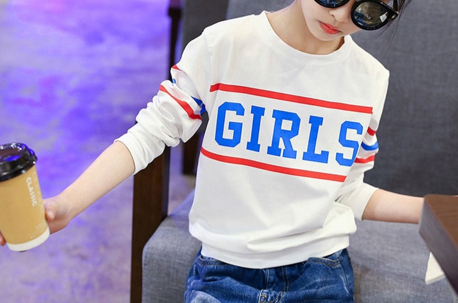 A young girl wearing a long sleeve shirt from True Radiant Treasures. The shirt is made from a soft polyester and cotton blend and comes in a variety of colors and patterns.