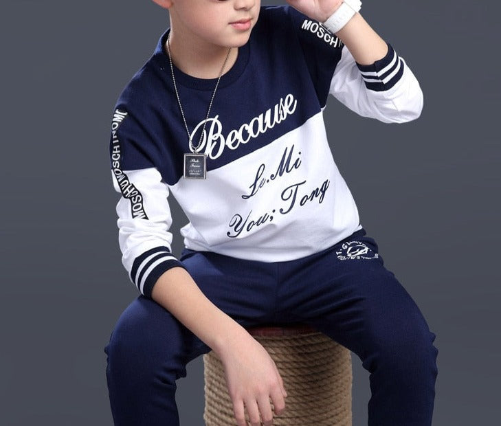 Boy wearing a casual clothing set made of 100% cotton and polyester, featuring a stylish combination of white and blue. Perfect for school, pair it with his favorite sneakers for a fashionable look.