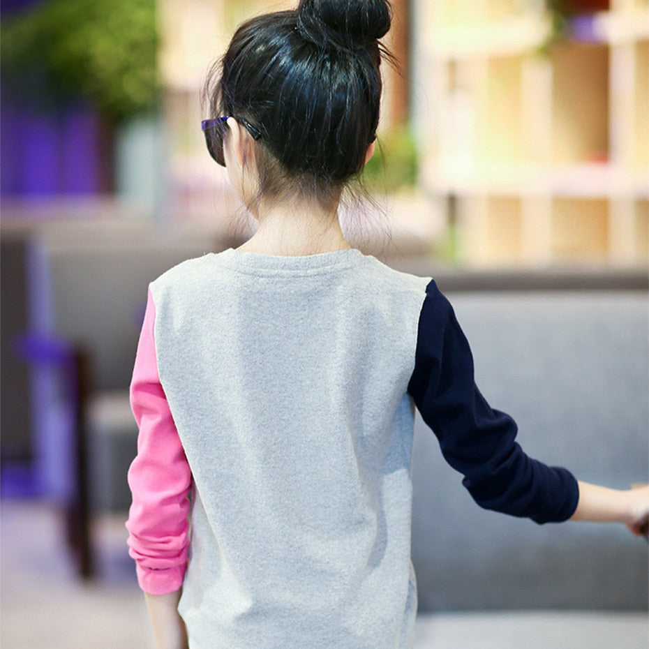 A young girl wearing a long sleeve shirt from True Radiant Treasures. The shirt is made from a soft polyester and cotton blend and comes in a variety of colors and patterns.